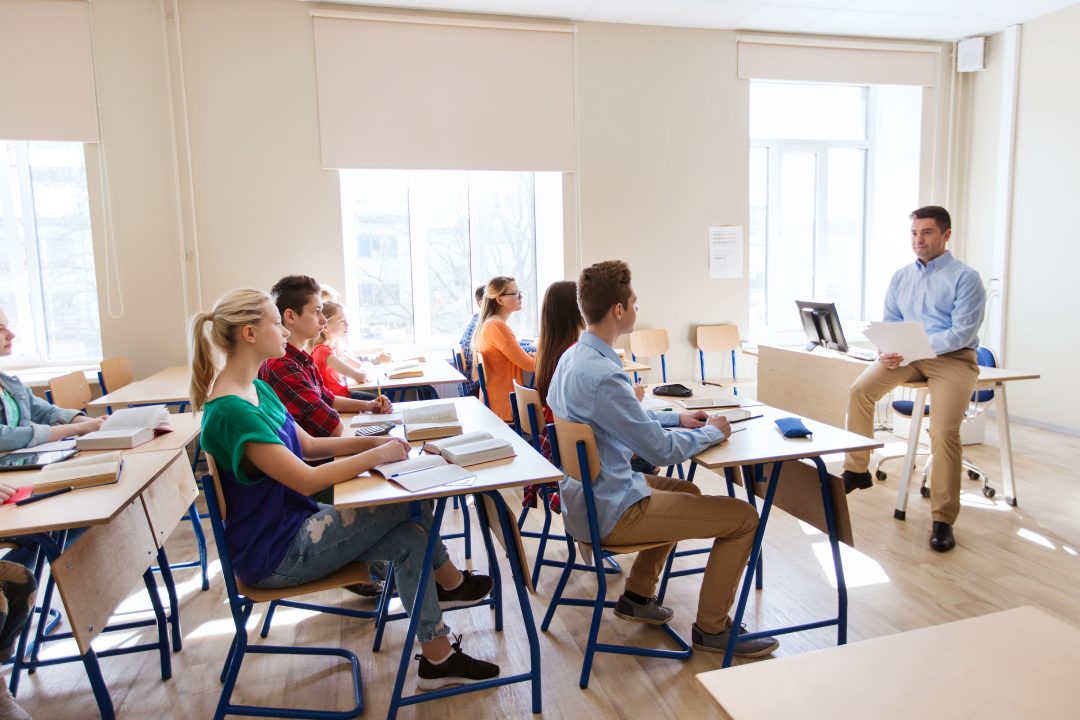 education, school and people concept - group of happy students and teacher with papers or tests