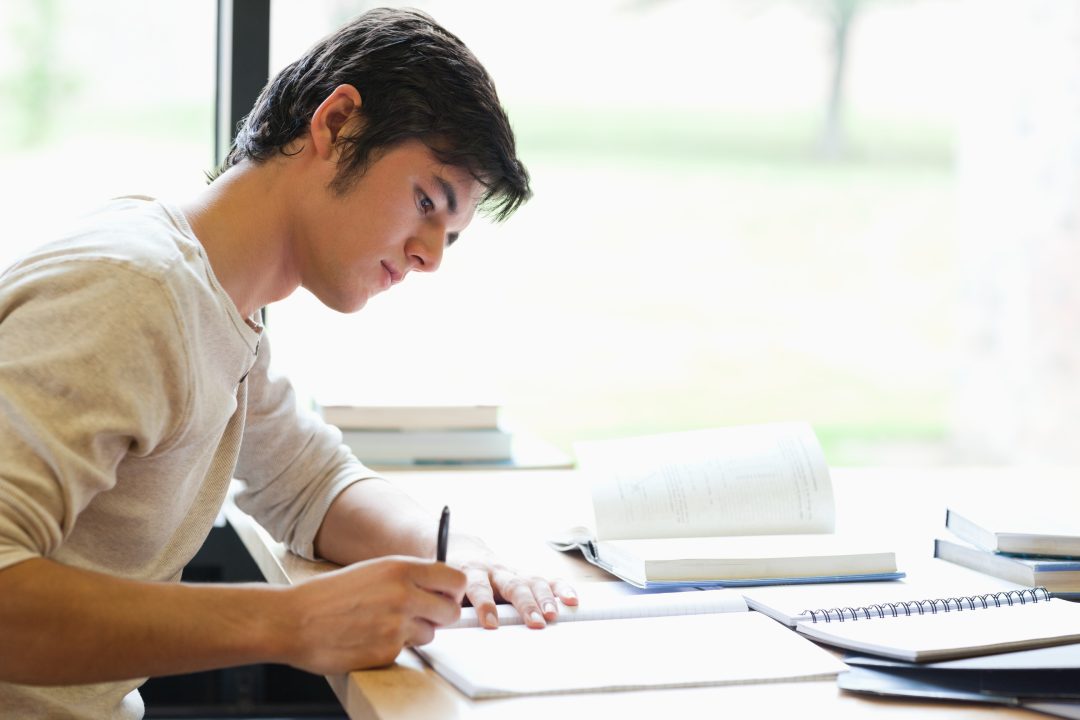 Serious male student writing in a laboratory