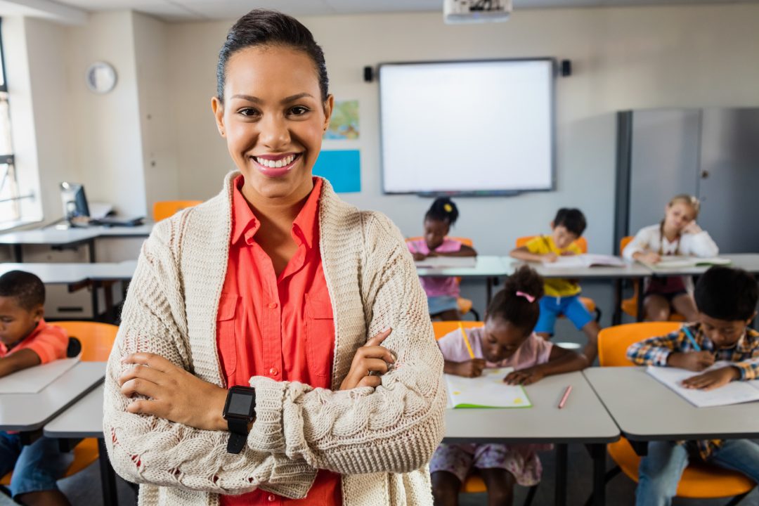 Portrait of smiling teacher standing in classroom