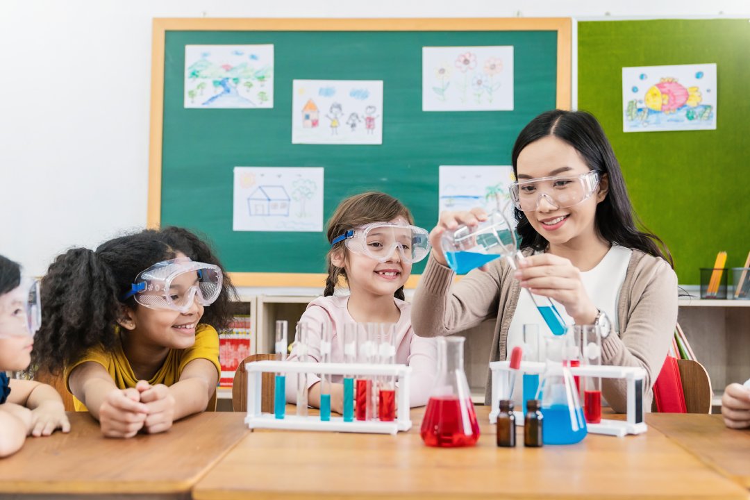 Diversity children doing a chemical experiment in laboratory at school. Portrait of happy kids at elementary school learning science chemistry with asian teacher. Fun study back to school concept.