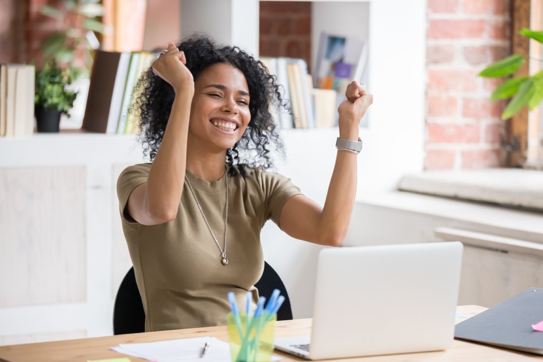 Emocionado mujer afroamericana se sientan en el escritorio se sienten eufóricos ganar la lotería en línea, feliz mujer negro overjoyed recibir correo en la computadora portátil de ser promovido en el trabajo, chica birracial sorprendido leer buenas noticias en la computadora