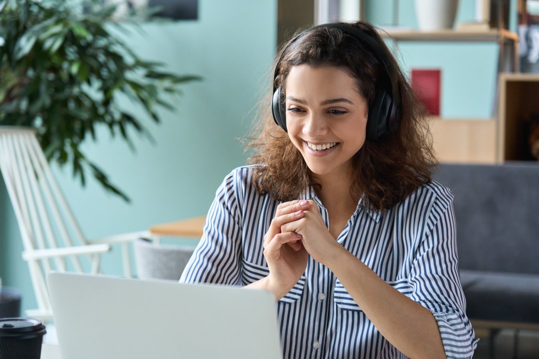 Happy latin hispanic girl college student wearing headphones watching distance online class, remote university webinar or having talk on laptop video conference call virtual meeting at home or campus.