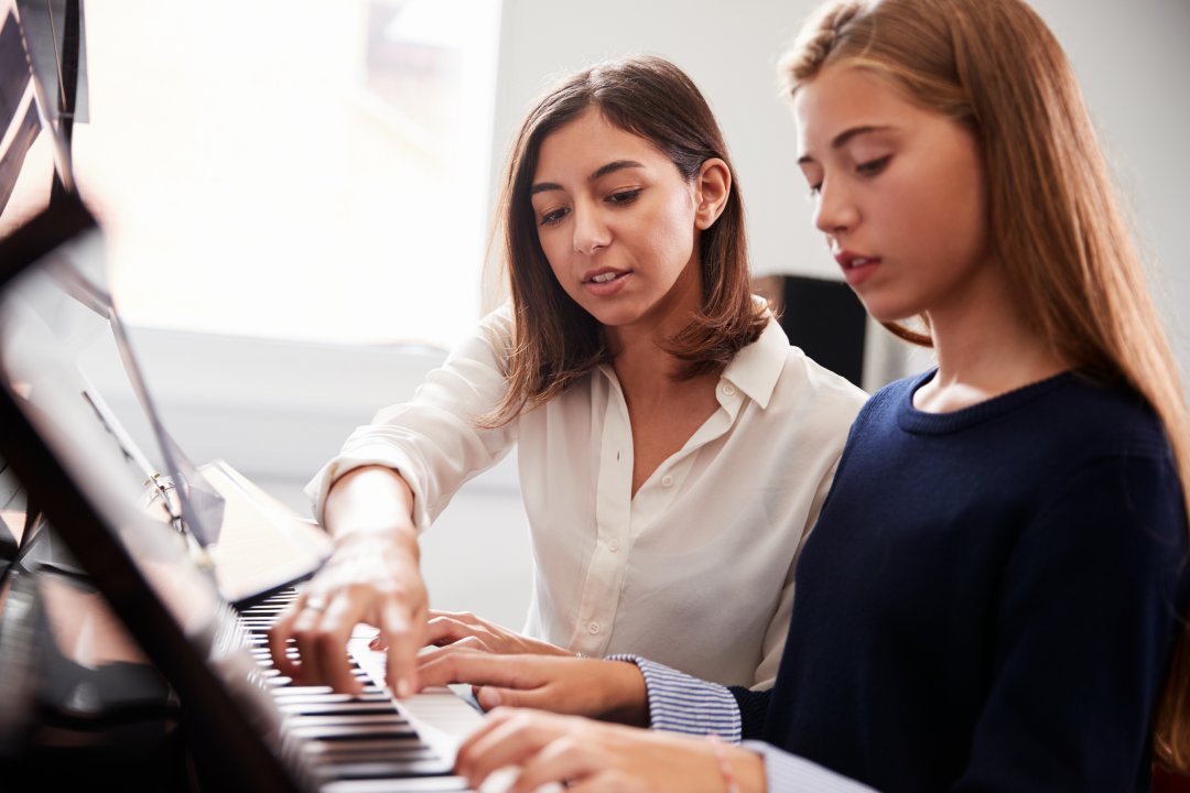 Alumna con profesor tocando el piano en clase de música