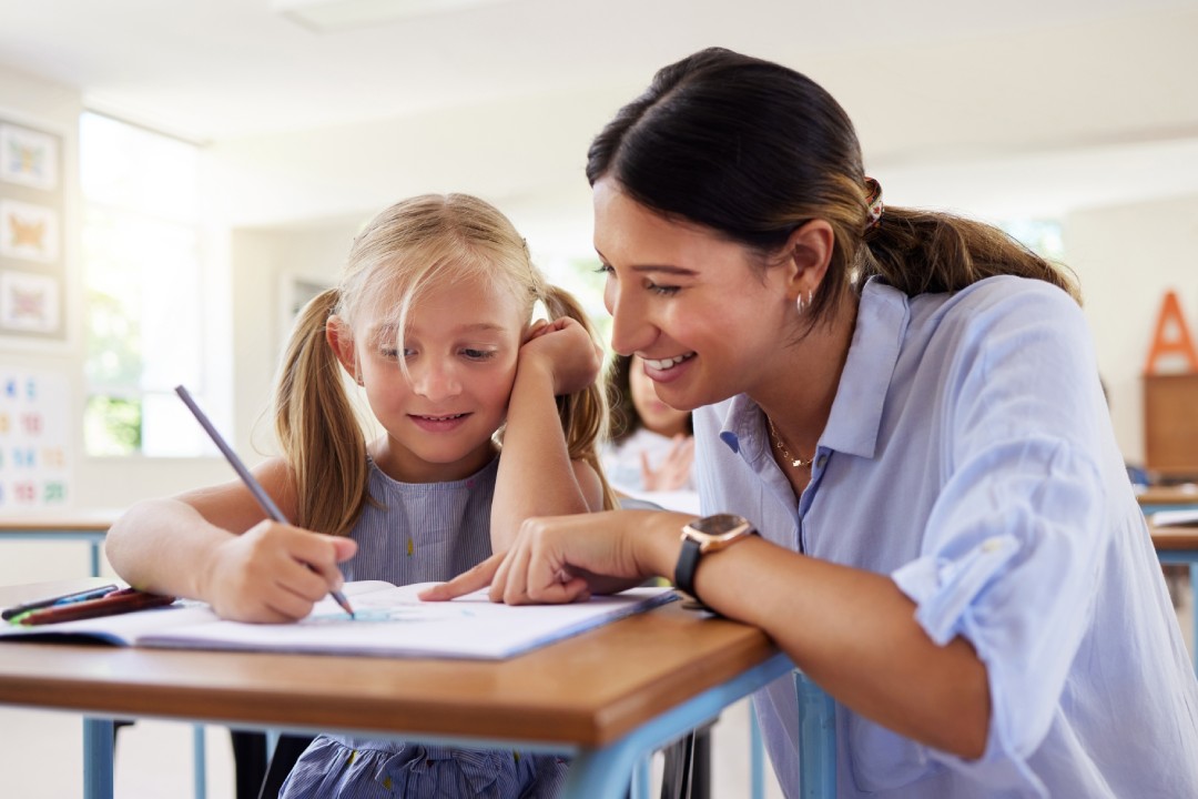 Teacher, learning and helping girl in classroom for drawing, studying or assessment.