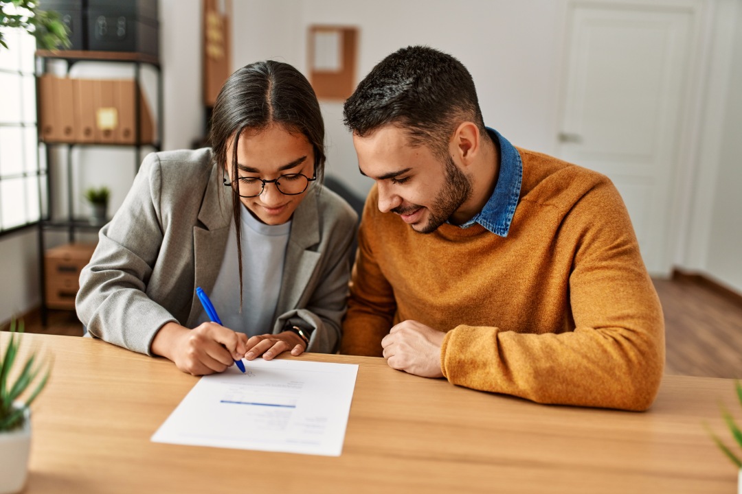 Couple smiling happy reading document at the office