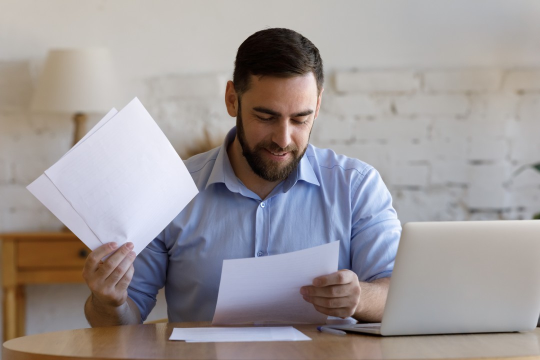 Hombre de negocios sonriente y satisfecho haciendo papeleo