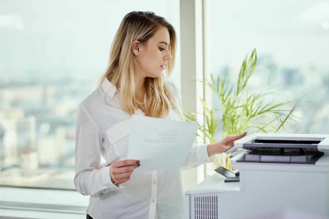 una joven empresaria imprime en la impresora de la oficina