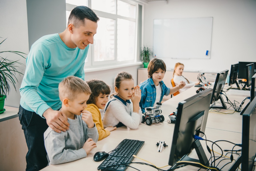 joven profesor feliz ayudando a sus alumnos adolescentes con el robot diy en la clase de educación stem