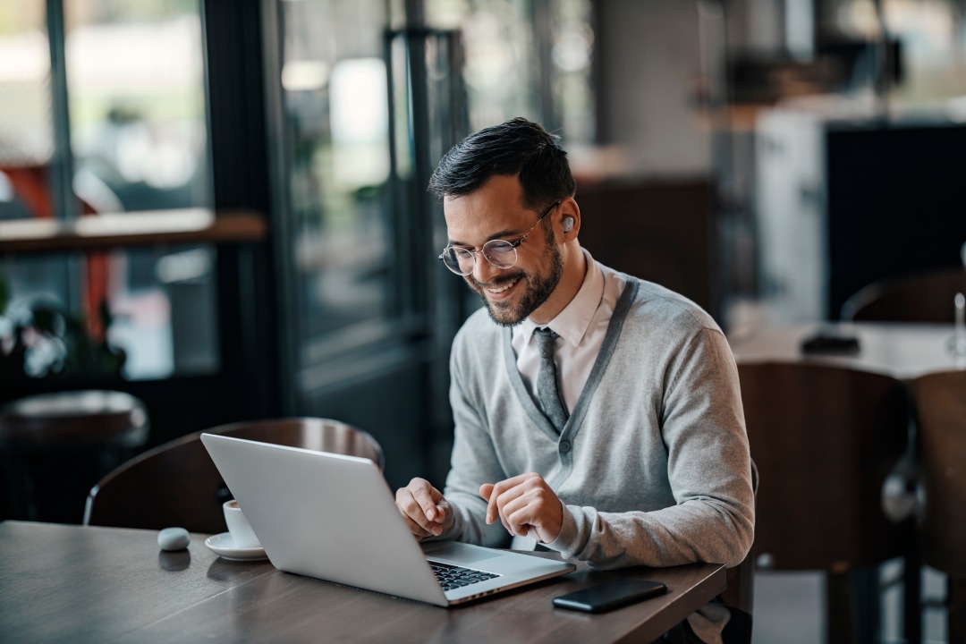 A young trendy businessman is using his laptop in a coffee shop.