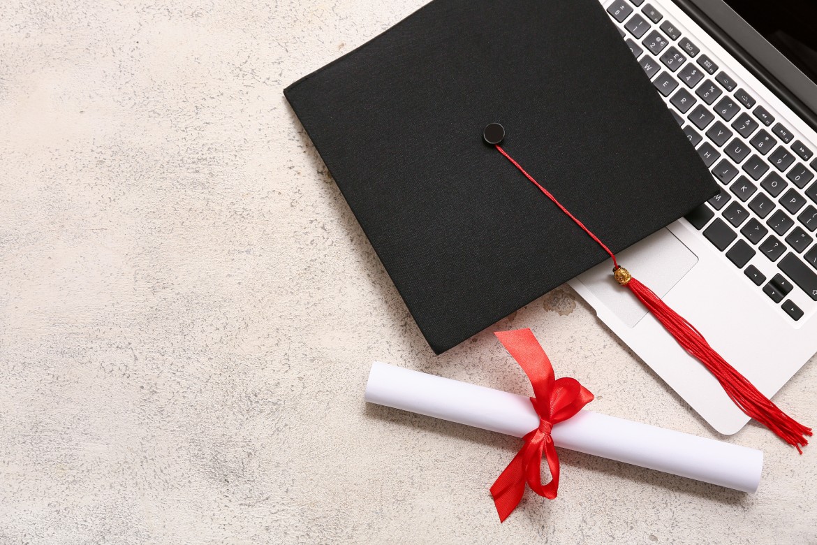 Diploma con cinta roja, portátil moderno y sombrero de graduación sobre fondo blanco grunge
