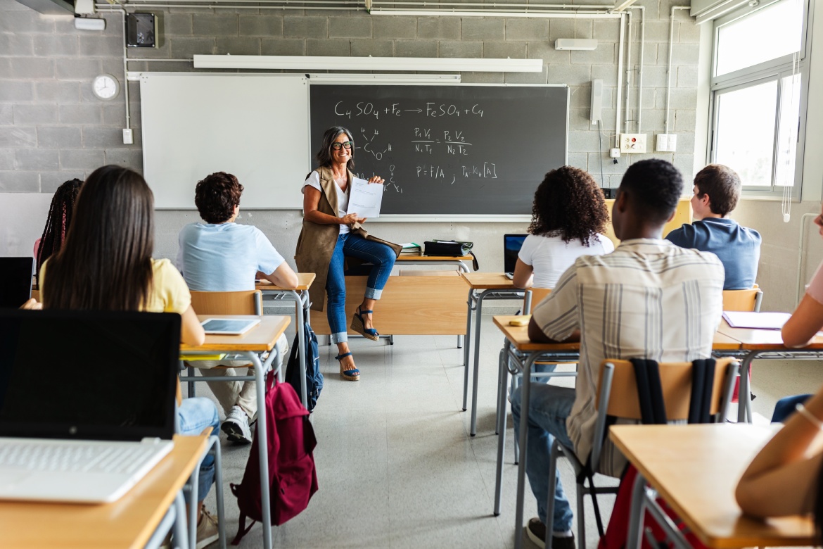 Joven grupo de estudiantes de la generación z asistiendo a clase en el instituto. Joven estudiante negro haciendo una pregunta a una profesora durante una clase. Concepto de educación