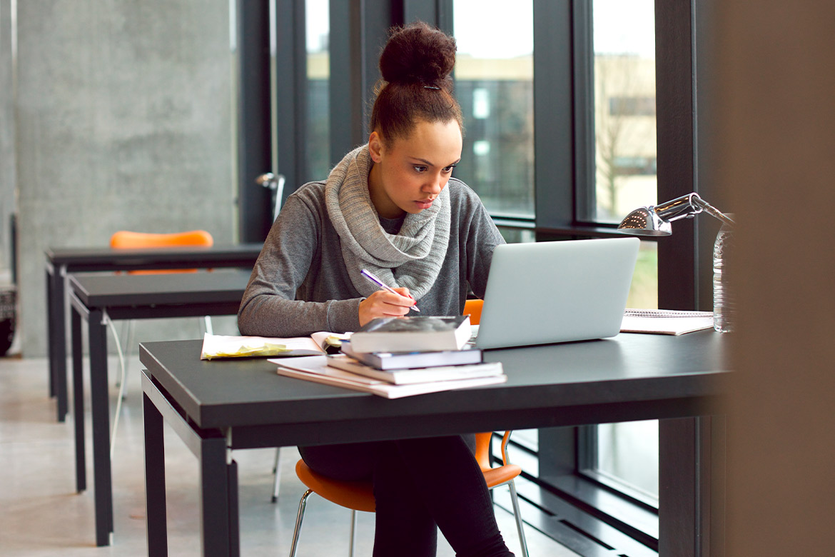 woman at desk studying, using computer.