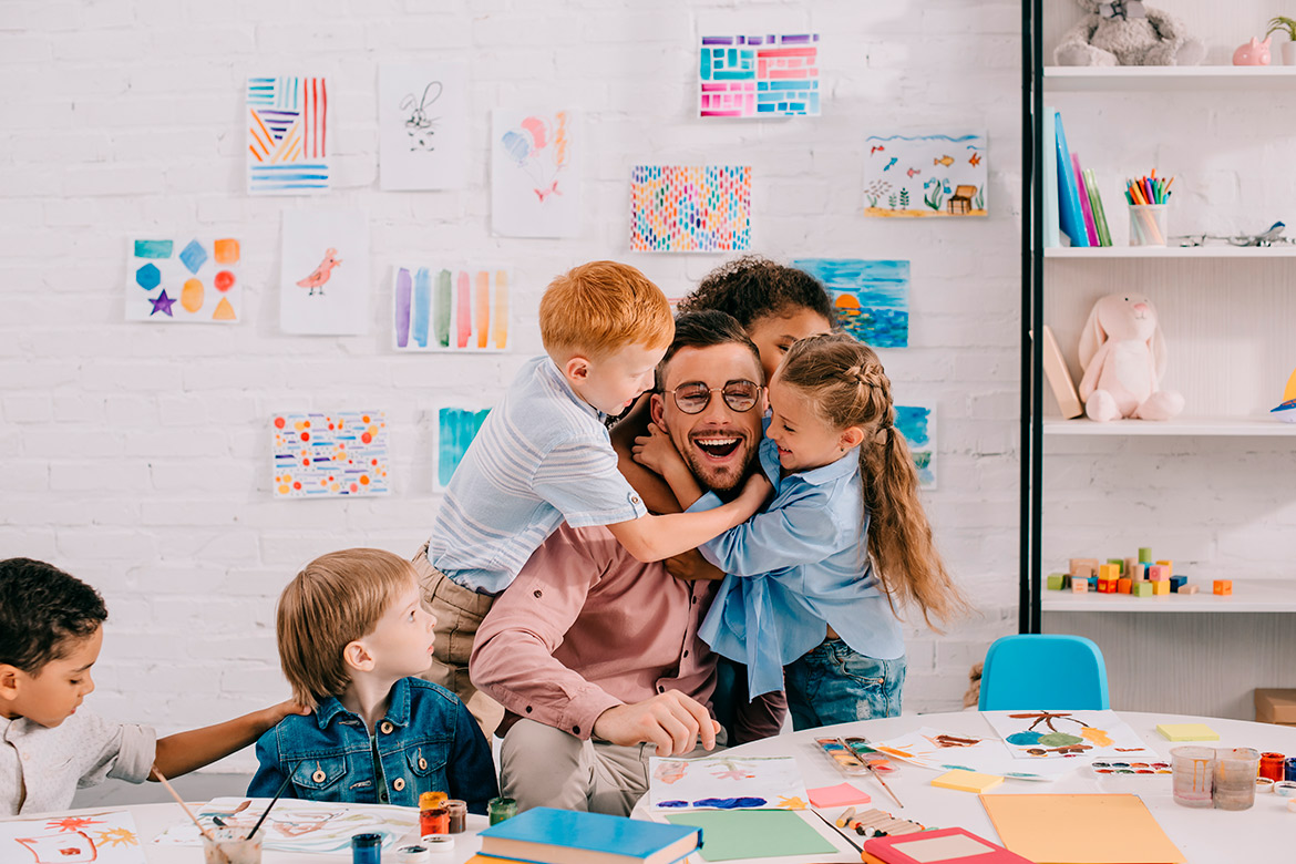 happy teacher being hugged by students