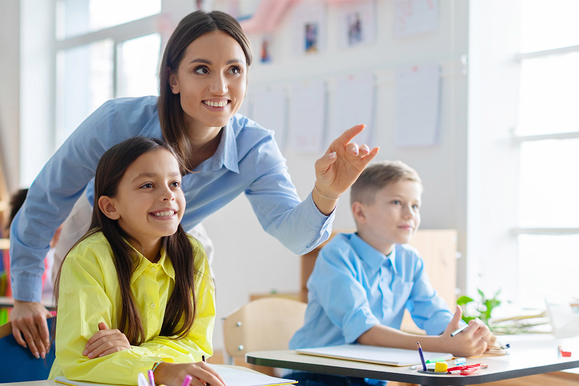 woman smiling and teaching students. Pointing in front. 