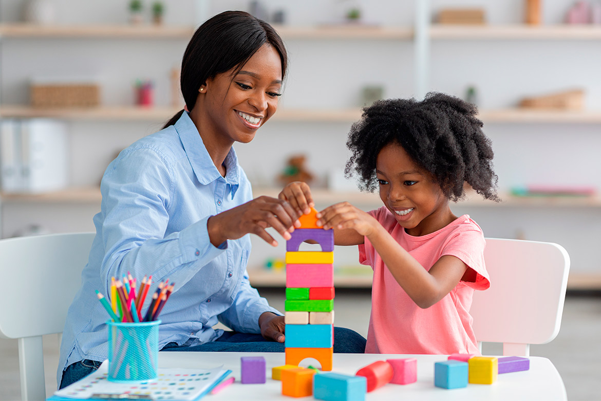A woman and a child engaged in play, stacking colorful blocks together on a surface.

