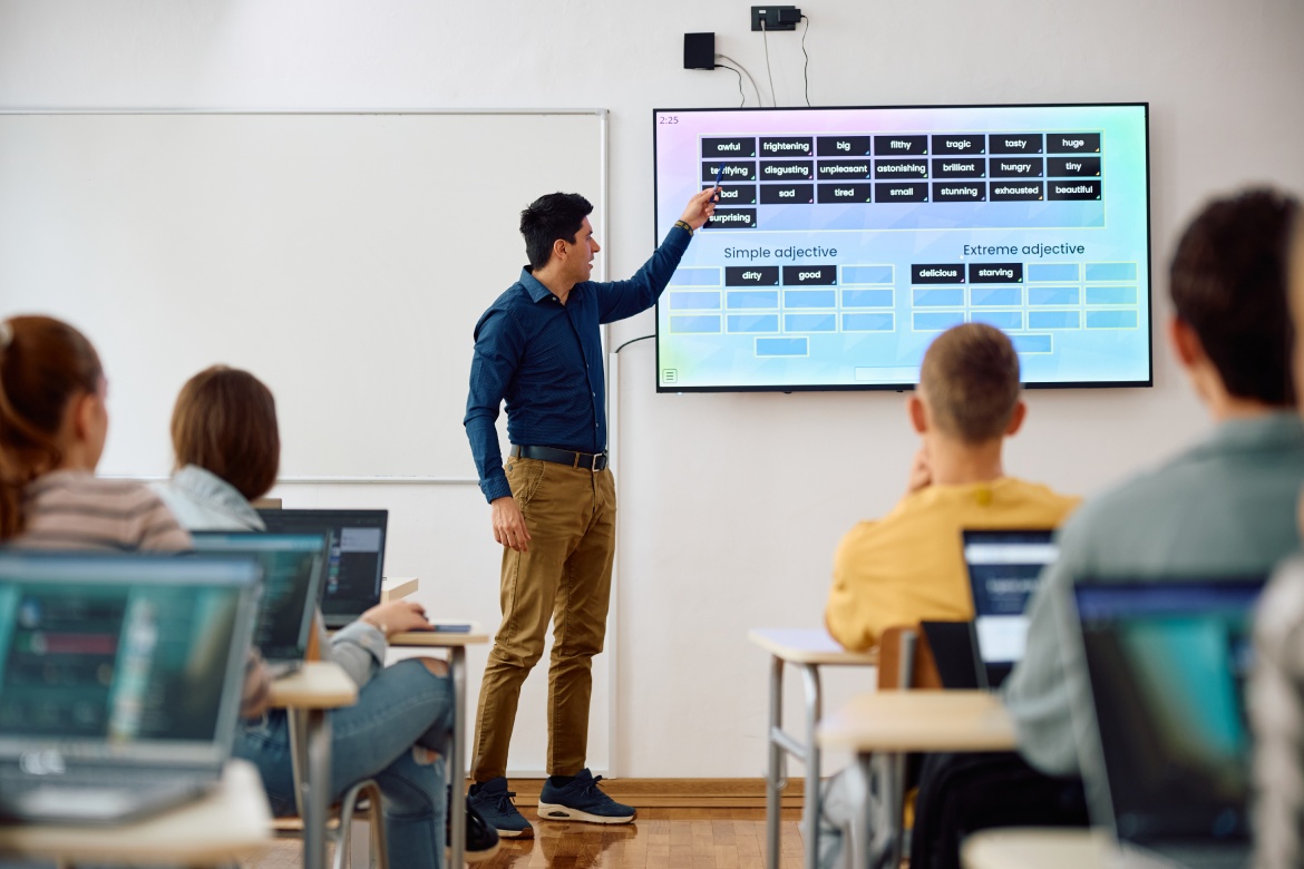 Substitute teacher using interactive whiteboard while giving a lesson to high school students in the classroom.