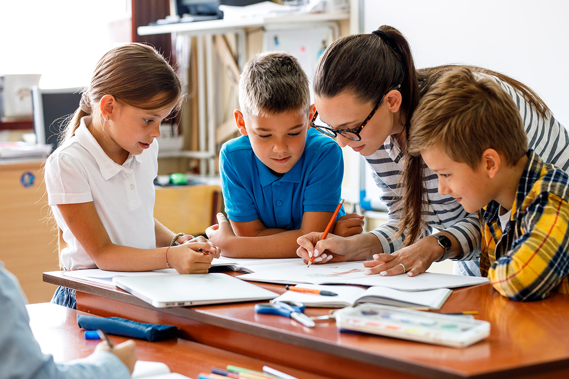  In a classroom, a teacher guides students as they work on their homework, promoting engagement and understanding.