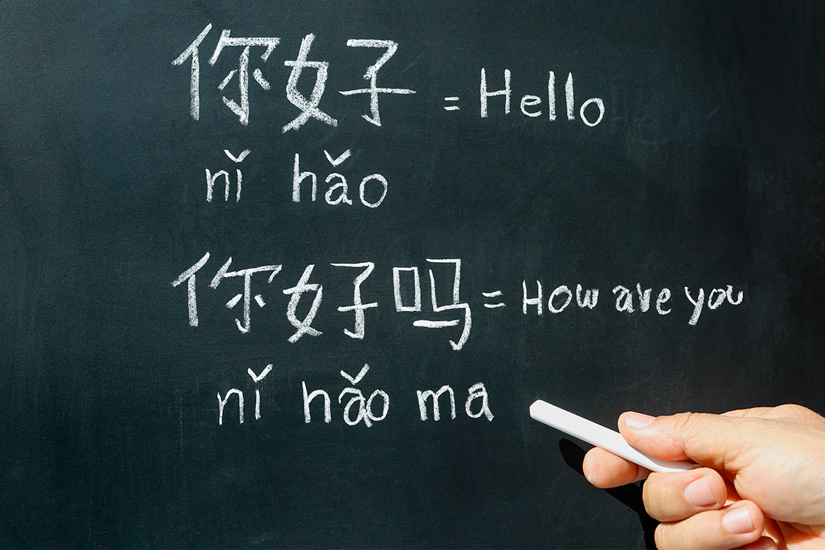 A person writing Chinese characters on a blackboard, illustrating a lesson on becoming a Chinese teacher in Texas.