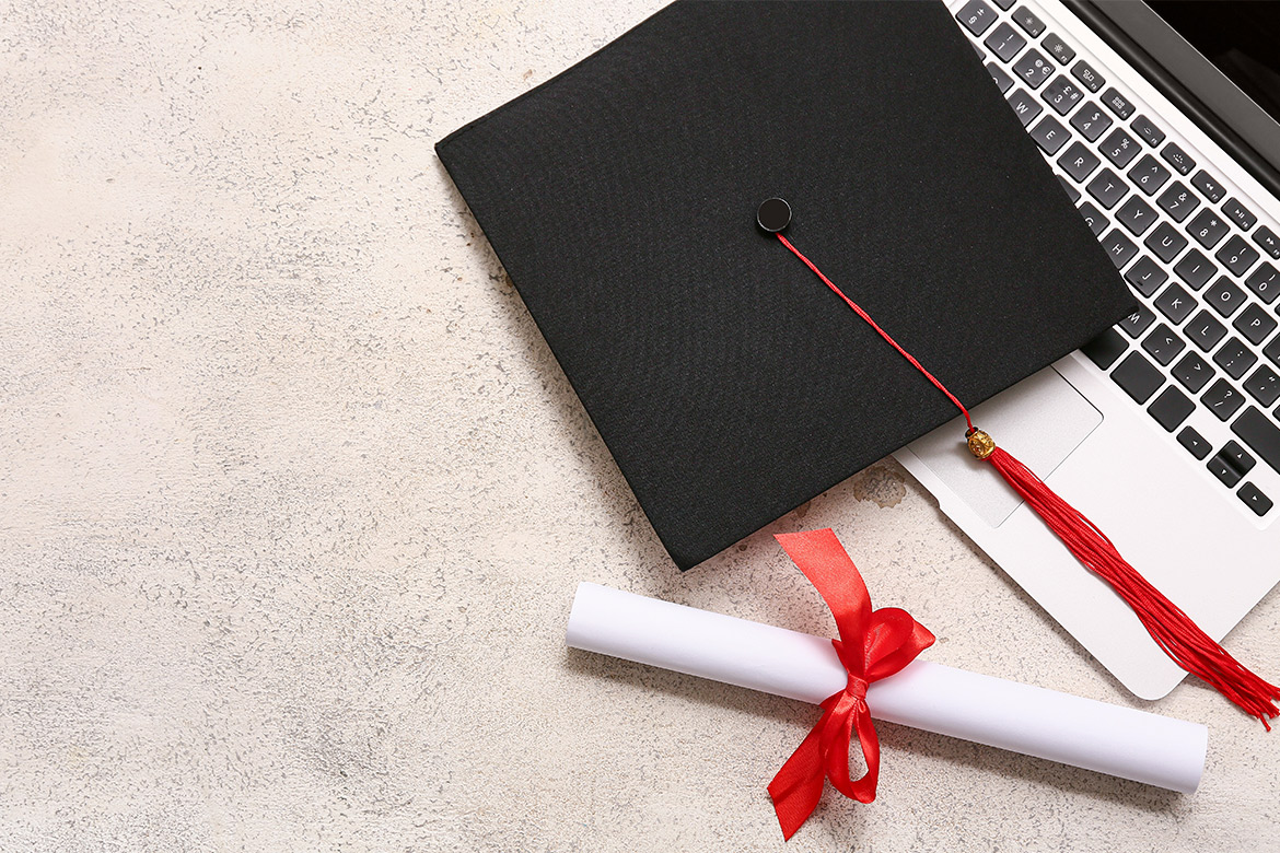 A graduation cap, laptop, and diploma placed on concrete, representing the Texas Online Alt Cert Guide for career changers.