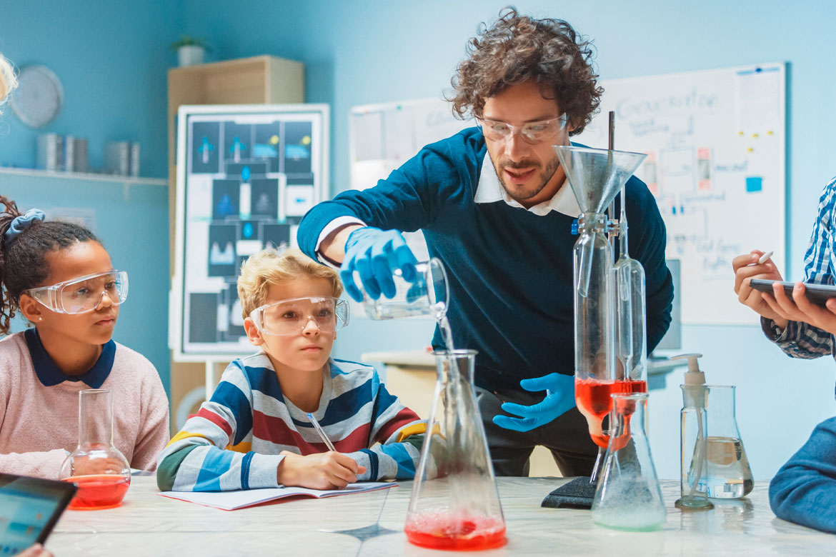 Elementary School Chemistry Classroom: Enthusiastic Teacher Teaches Diverse Group of Children Shows Science Reaction Experiment by Mixing Chemicals in Beaker so they Shoot Foam (Elephant Toothpaste)