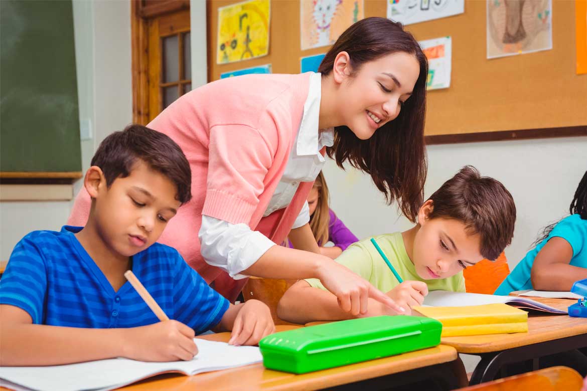 Smiling teacher helping a student at the elementary school